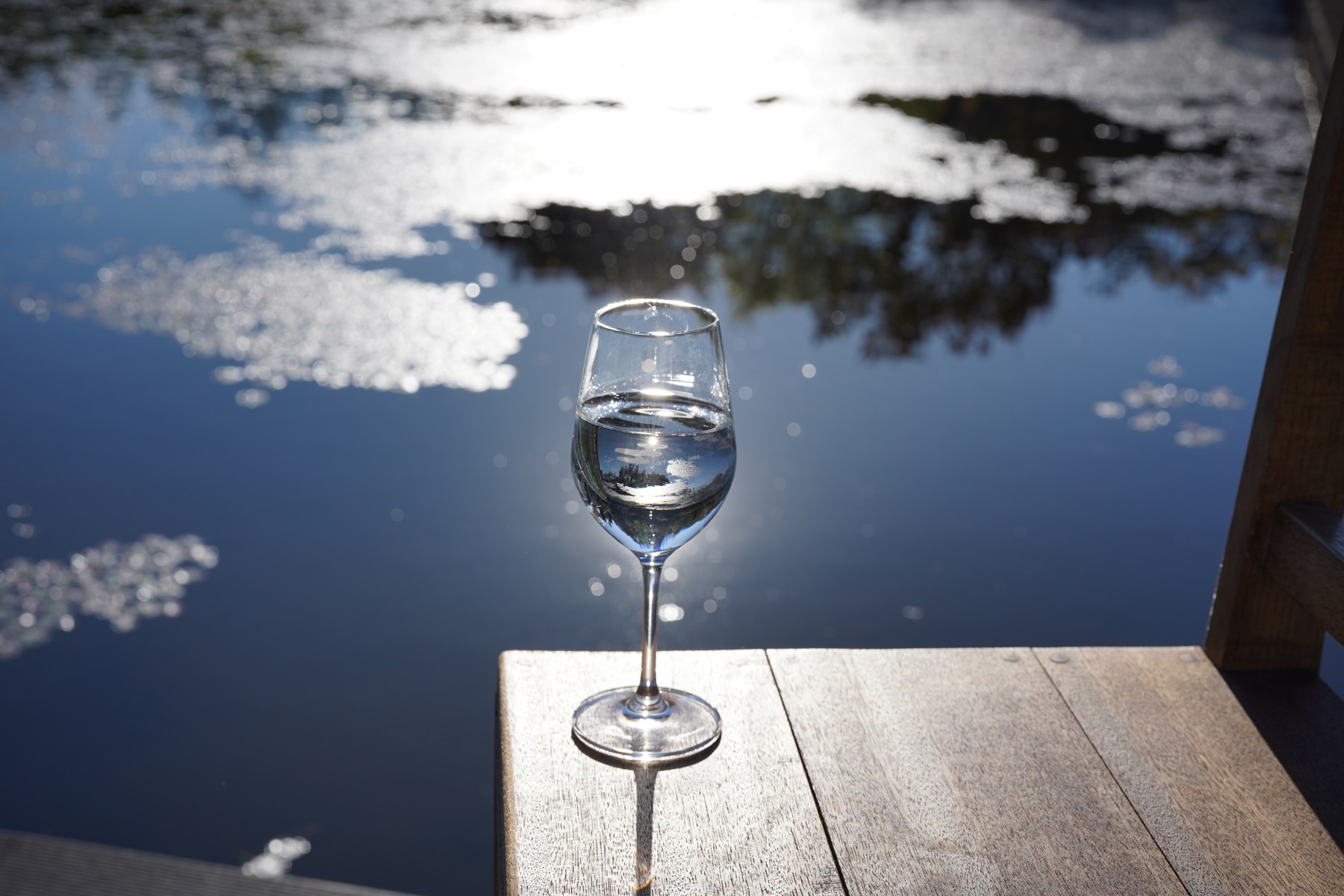 Wine glass on a wooden table overlooking the water